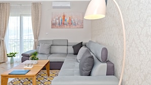 Ein modernes Wohnzimmer mit einem grauen Ecksofa, einem Holztisch und einer Stehlampe.