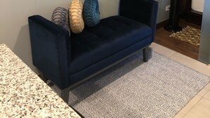 Een moderne woonkamer met een donkerblauwe bank, een getextureerd vloerkleed en een stadslandschap schilderij aan de muur.