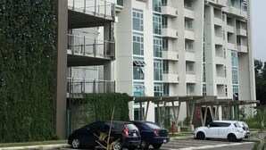 Een meerlaags woongebouw met balkons, een parkeerplaats en een groene wand.