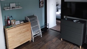 A room with a wooden dresser, a TV stand, a clock, and a door leading to another room. - Ferienhaus in See Nähe! Ruhige Lage. Wlan, Bettwäsche und Handtücher Inkl (Klein Sien)