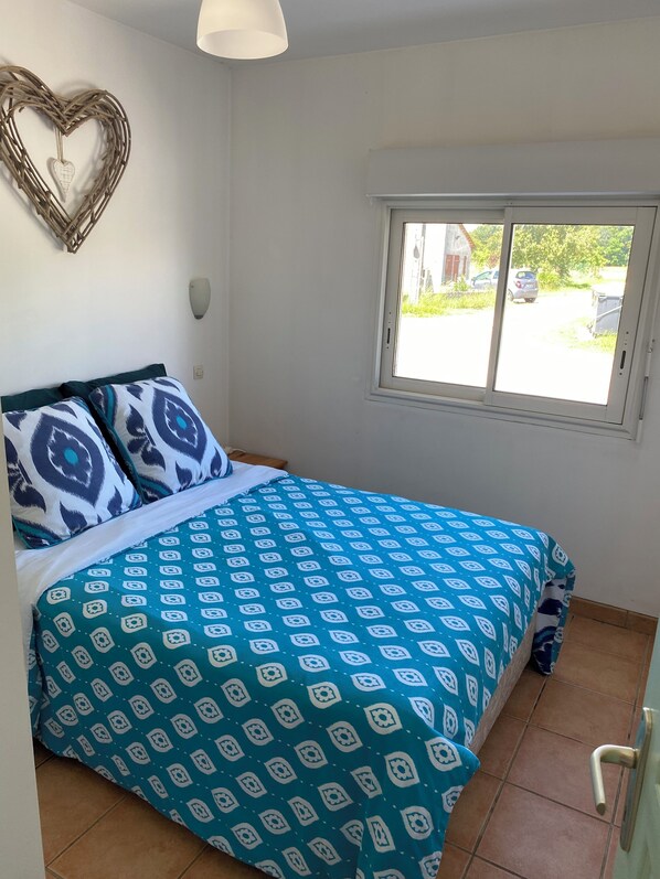 A bedroom with a bed, a window, and a heart-shaped decoration on the wall. - Chez Desire (EI) our Peaceful, cosy 2 bedroom gite, with private heated pool! (Saint-Simon-de-Bordes)