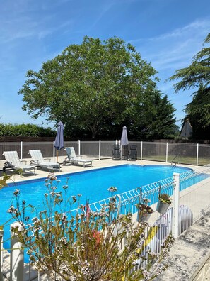 A swimming pool with lounge chairs and umbrellas, surrounded by a white fence and trees. - Chez Desire (EI) our Peaceful, cosy 2 bedroom gite, with private heated pool! (Saint-Simon-de-Bordes)