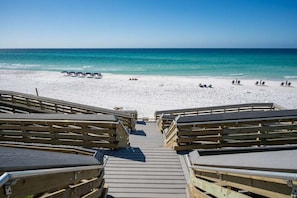 Un muelle de madera que conduce a una playa de arena blanca y agua azul cristalina.