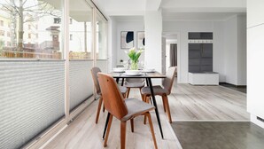 A modern kitchen with a dining area, large windows, and a view of buildings outside.