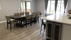 A modern kitchen with a central island, dark wooden dining table, and light grey walls.