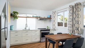 Una cocina moderna con armarios blancos, una mesa de comedor de madera y un horno empotrado.