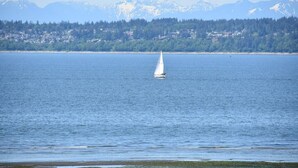 A sailboat on a calm body of water with a mountainous backdrop and a forested shoreline. - Peaceful Beachfront Getaway with Sweeping Water Views (Blaine)