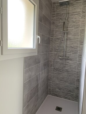 Enjoy a refreshing shower experience with a handheld and rain showerhead, set against a textured tile backdrop.
