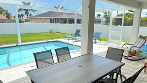 Un espace extérieur abrité comprenant une piscine, une table et des chaises.