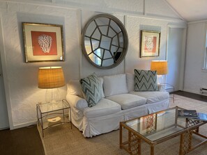 Relax in a stylish living room with a comfortable sofa, geometric mirror, and functional coffee table.