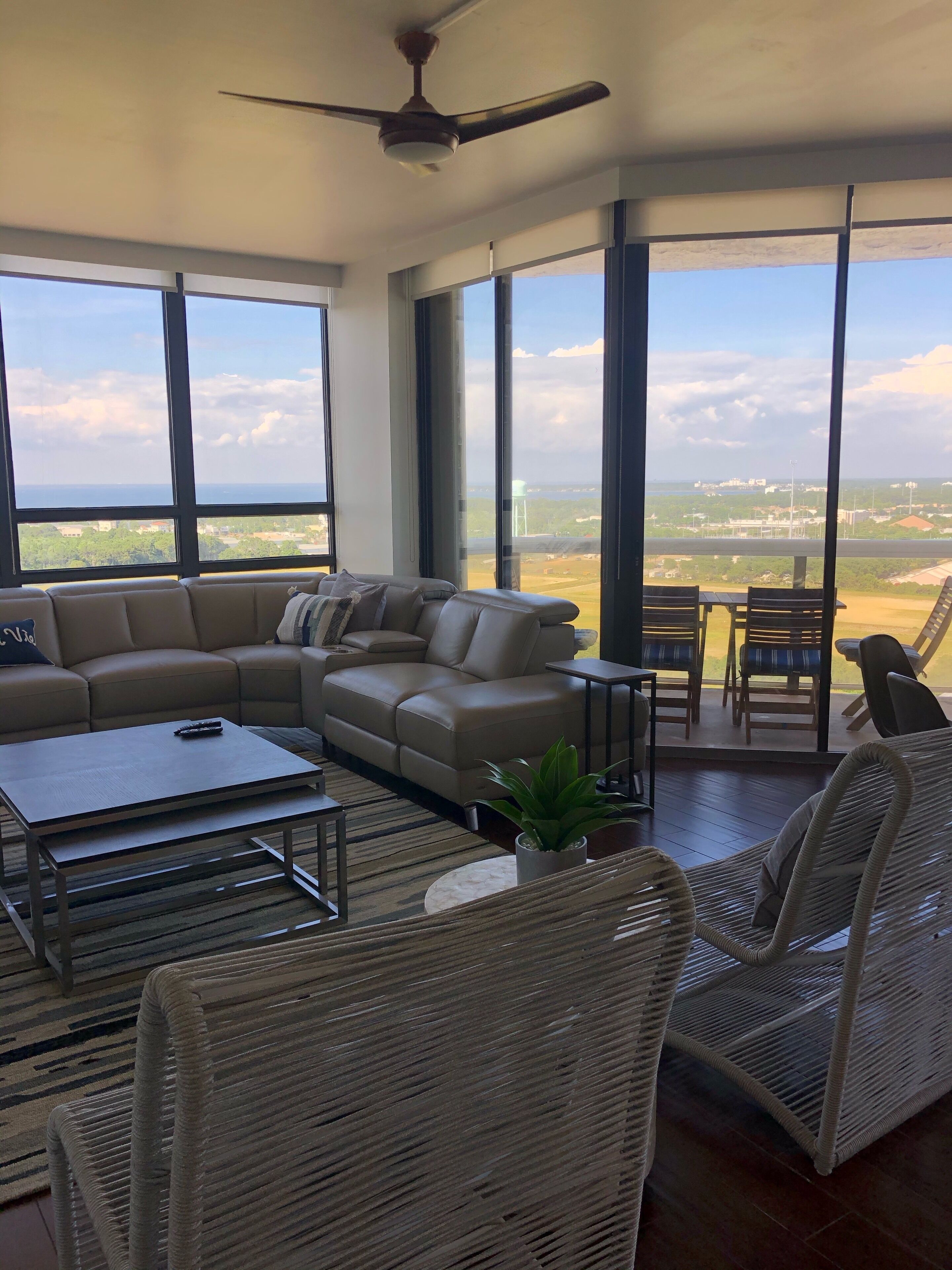 A spacious living room with a large sofa, a coffee table, and wicker chairs.