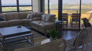 A spacious living room with a large sofa, a coffee table, and wicker chairs. - PENTHOUSE -16TH FLOOR with FREE BEACH SERVICE.  AMAZING VIEW!! (Miramar Beach)