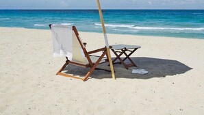 A beach umbrella, a beach chair, and a small table on a sandy beach with the ocean in the background. - PENTHOUSE -16TH FLOOR with FREE BEACH SERVICE.  AMAZING VIEW!! (Miramar Beach)