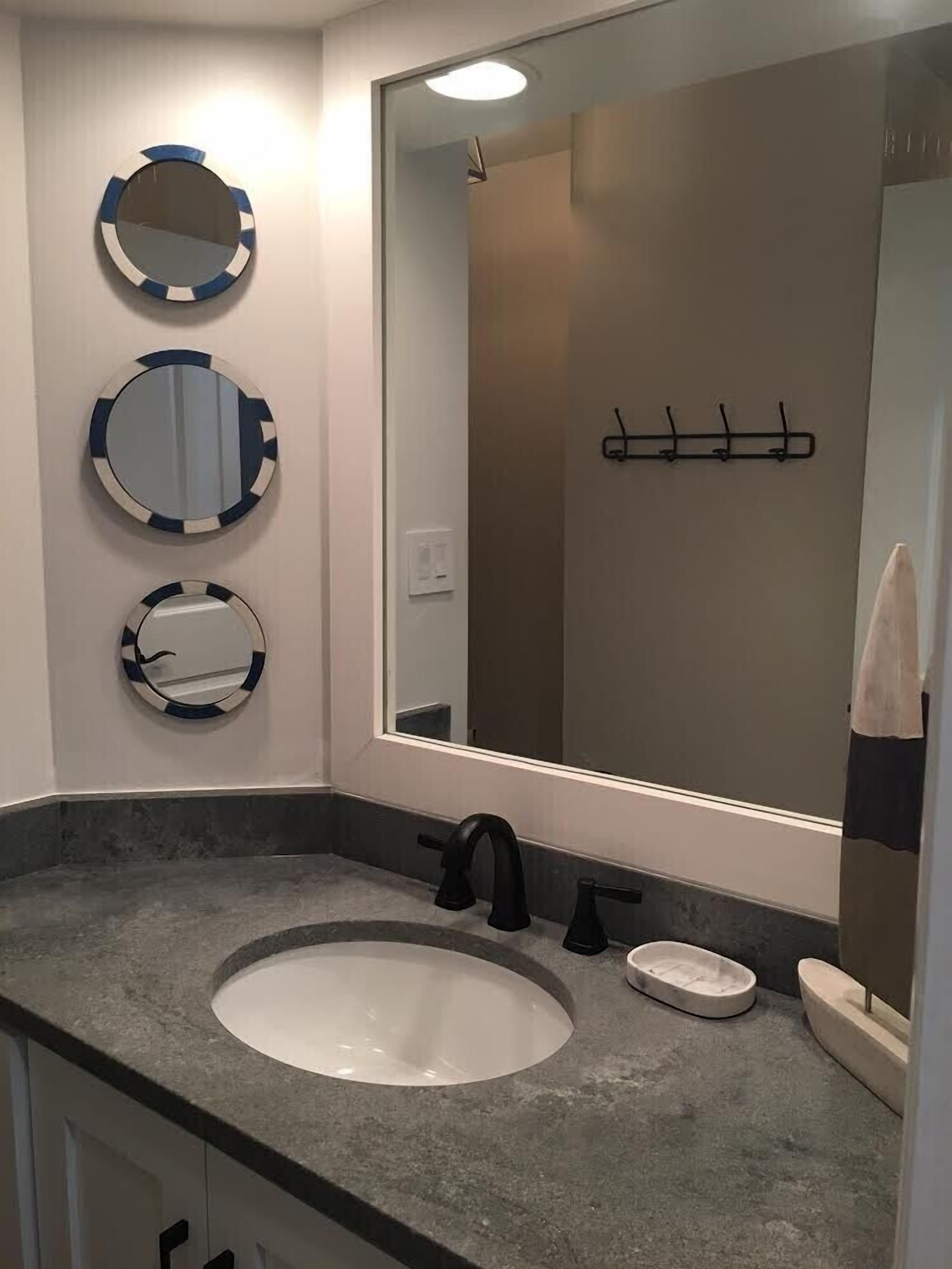 A bathroom with a large mirror, three smaller mirrors, a sink, and a towel rack.