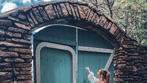 A woman approaching a stone archway leading to a teal door with a metal handle. - Beech Mtn- Amazing View+1 Mile to Ski Beech - Walking distance to Overlook Barn (Beech Mountain)