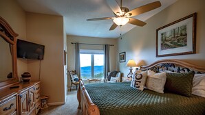 A bedroom with a bed, a ceiling fan, a TV, a dresser, a chair, and a window with a view. - Beech Mtn- Amazing View+1 Mile to Ski Beech - Walking distance to Overlook Barn (Beech Mountain)