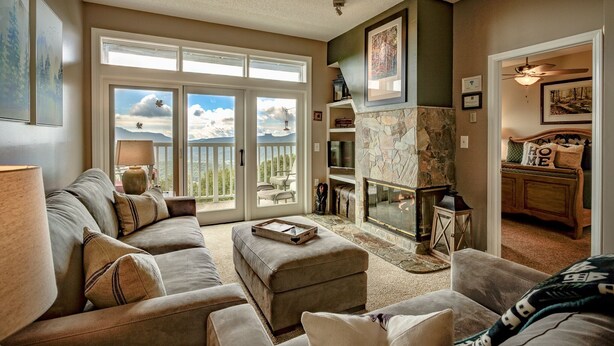 A living room with a stone fireplace, a sofa set, and a dining area with a wooden table and chairs. - Beech Mtn- Amazing View+1 Mile to Ski Beech - Walking distance to Overlook Barn (Beech Mountain)