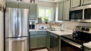 A modern kitchen with stainless steel appliances, green cabinets, and a window with blinds. - Beech Mtn- Amazing View+1 Mile to Ski Beech - Walking distance to Overlook Barn (Beech Mountain)