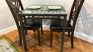 Una mesa de comedor con cuatro sillas, un mantel individual verde y dos platos.