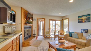 A cozy living room with a sofa, coffee table, and a dining area with chairs. - Schuss Mountain Resort Condo: Steps to Golf! (Mancelona)