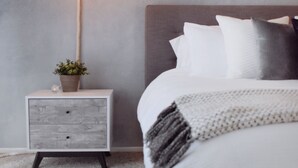 Une chambre à coucher comprenant un lit, une table de chevet, une lampe et un mur à la finition texturée.