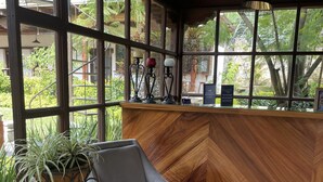 Ein Empfangsbereich mit einem Holzbüro, einem grauen Sessel und einem Blumentopf.