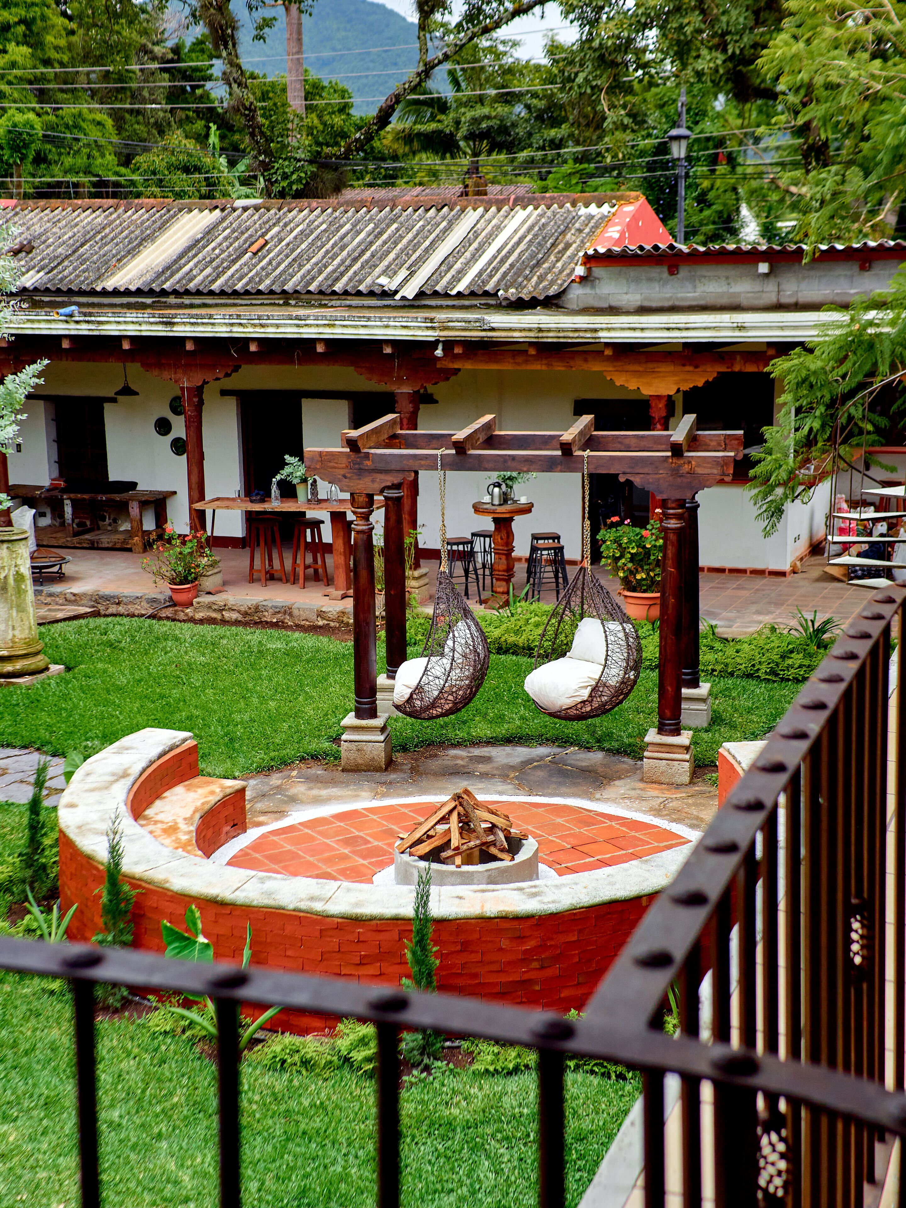 A traditional house with a tiled roof, a wooden porch, and a circular fire pit.