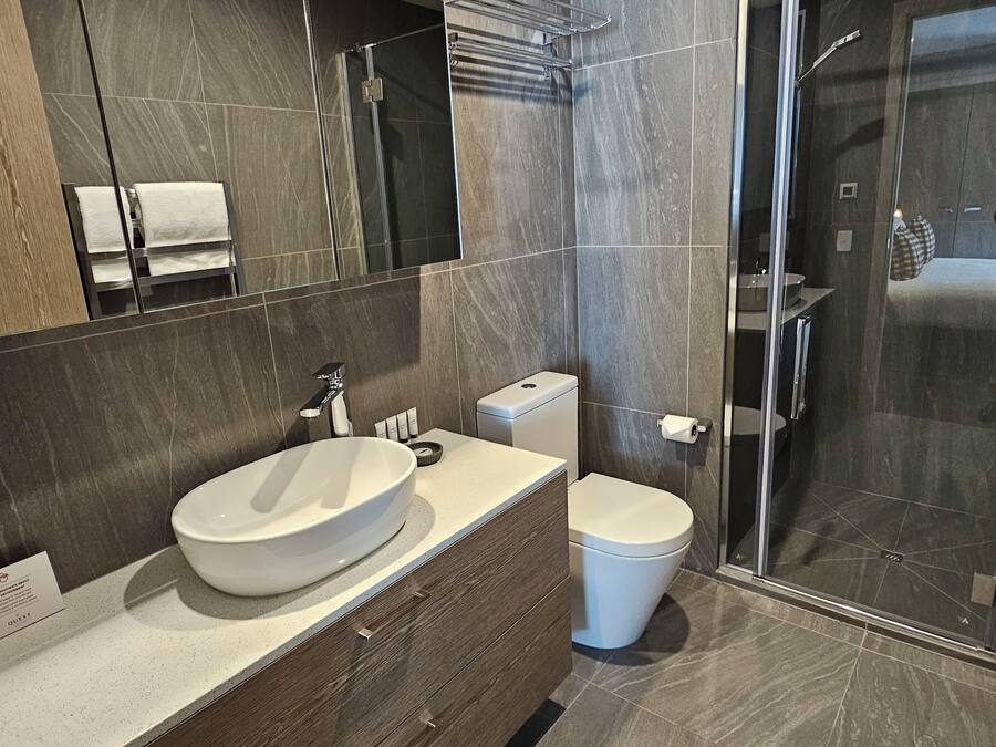 A modern bathroom with a large sink, toilet, and walk-in shower.