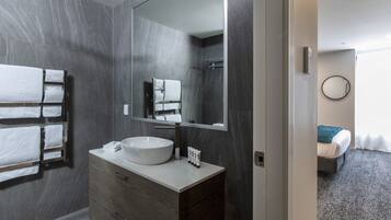 A modern bathroom with a large mirror, a white sink, and a towel rack.