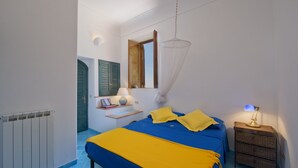 A bedroom with a bed, bedside table, lamp, and a window with a view. - Sweet Home (Praiano)