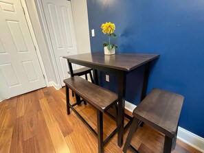 A dark wooden table with a bench, a small potted plant, and a blue wall in the background. - Downtown City Hall near Kimmel Center 2BD Suite (Philadelphia)
