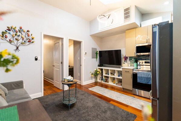 A compact living space with a kitchenette, a flat-screen TV, and a dining area. - Downtown City Hall near Kimmel Center 2BD Suite (Philadelphia)