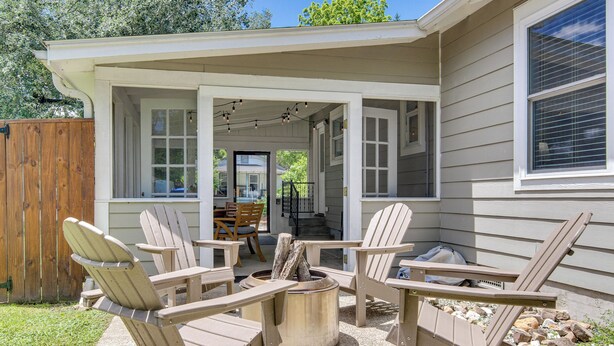 A covered patio with Adirondack chairs and a fire pit.