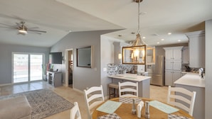 Un'ampia cucina con isola centrale, mobili bianchi e un moderno lampadario.