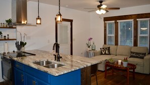 Eine moderne Küche mit blauen Schränken, einer Marmorarbeitsplatte und einer eingebauten Spüle.