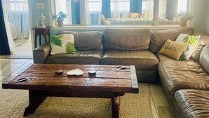 Een woonkamer met een bruine leren bank, een houten salontafel en een plafondventilator.