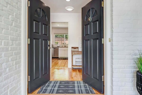A hallway with a dark door leading to a kitchen area. - Rincon Valley Wine Country Vacation Home (Santa Rosa)