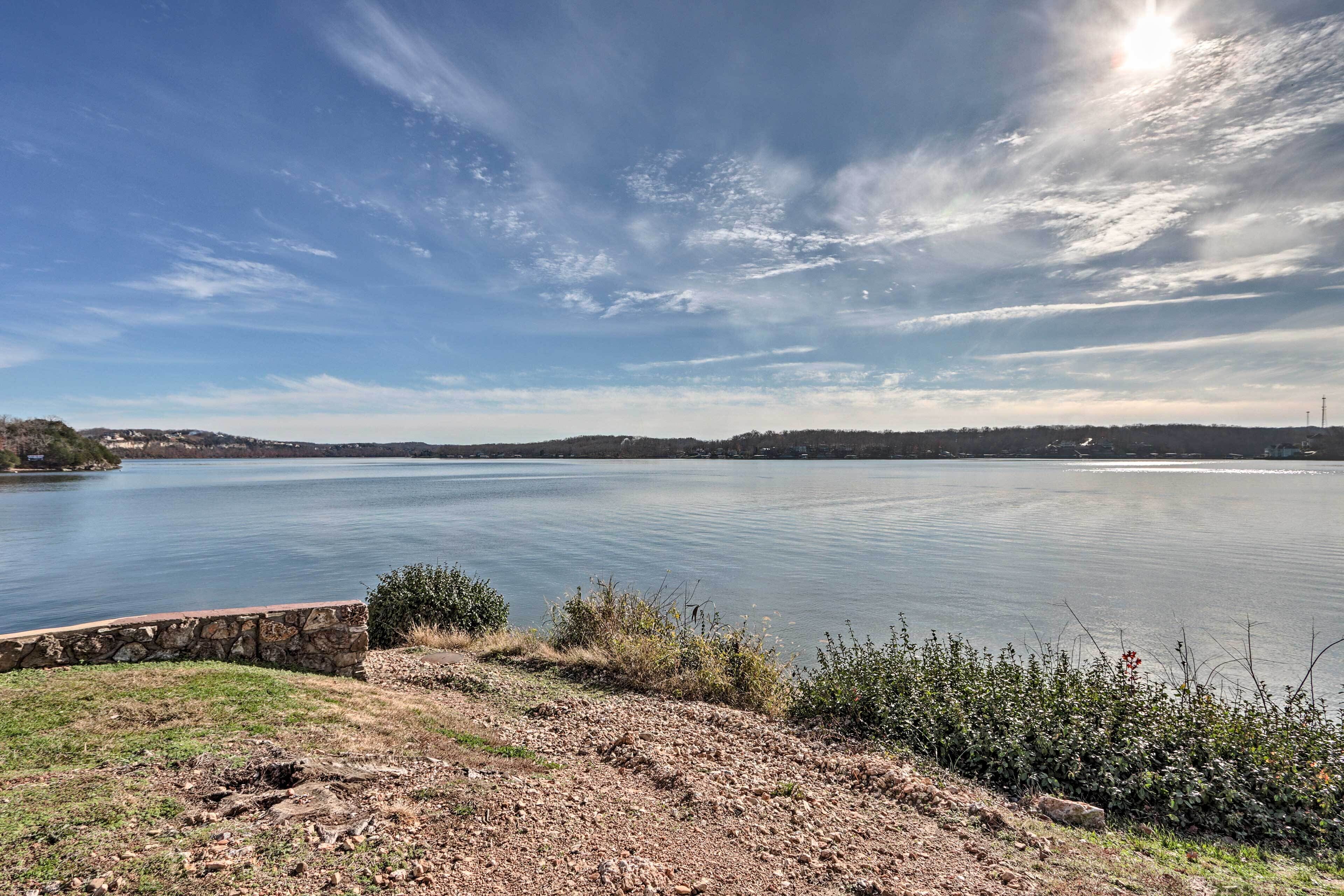 A lake with a stone wall and vegetation in the foreground.