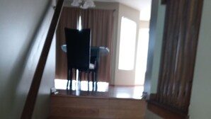 A wooden staircase leading to a dining area with a table and chairs.