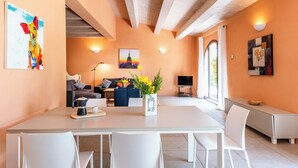 A modern living room with a dining area, featuring a sofa set, a coffee table with a flower vase, and artwork on the walls. - Villa Pesca - Cignella Resort Val D'orcia Toscana (Toscana)