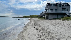 Ein Strandgrundstück mit einem mehrstöckigen Gebäude, das Balkone und eine Treppe zum Strand besitzt.