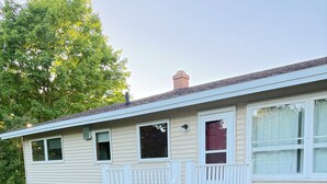 Une maison mobile dotée d’un porche à l’avant, d’une petite terrasse et d’un espace barbecue couvert.