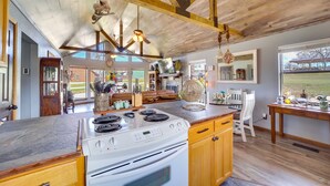 A spacious kitchen with a large island, wooden ceiling beams, and a view of the outdoors. - Incredible Log Home: 1 Mile from Lake Tenkiller (Vian)