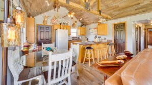 A rustic kitchen with wooden beams, a glass dining table, and a leather sofa. - Incredible Log Home: 1 Mile from Lake Tenkiller (Vian)