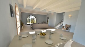 A dining area with a table set for four, a sofa in the background, and a staircase leading to another level. - Villa Cielo - Cignella Resort Toscana (Toscana)