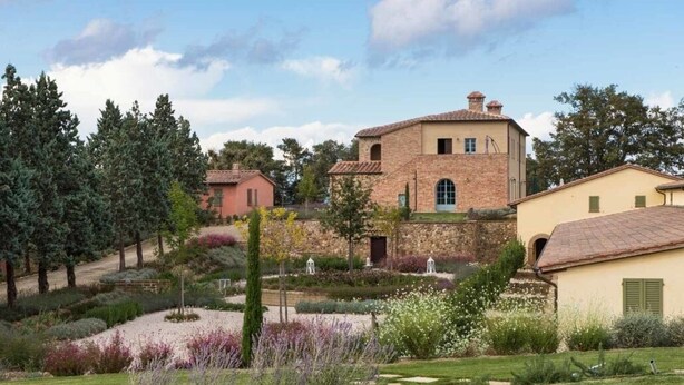 A traditional stone building with a tiled roof, surrounded by a well-maintained garden with various plants and a lawn. - Villa Cielo - Cignella Resort Toscana (Toscana)