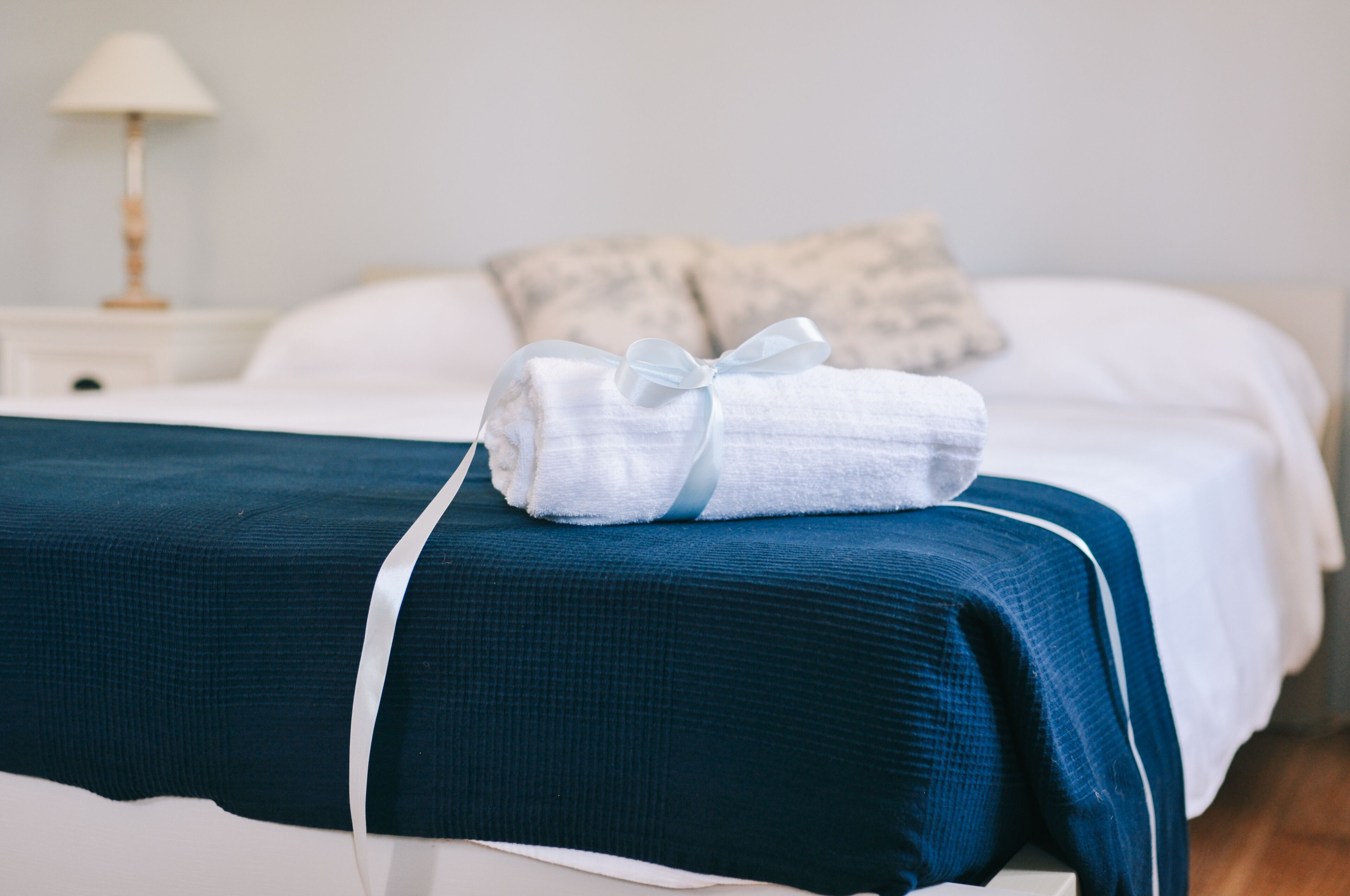 Una cama bien hecha con una toalla blanca y un edredón azul.