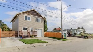 Une maison à deux étages avec un porche à l’avant, un garage et un petit jardin devant.