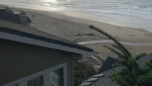 Uitzicht op een strand vanaf een gebouw, met een heldere lucht en de zon die in de oceaan ondergaat.