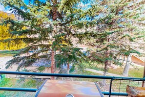 Enjoy a balcony with a view of the surrounding residential area, featuring a barbecue grill and serene views of trees and a nearby house.